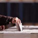 Hand of a person casting a vote into the ballot box during elections