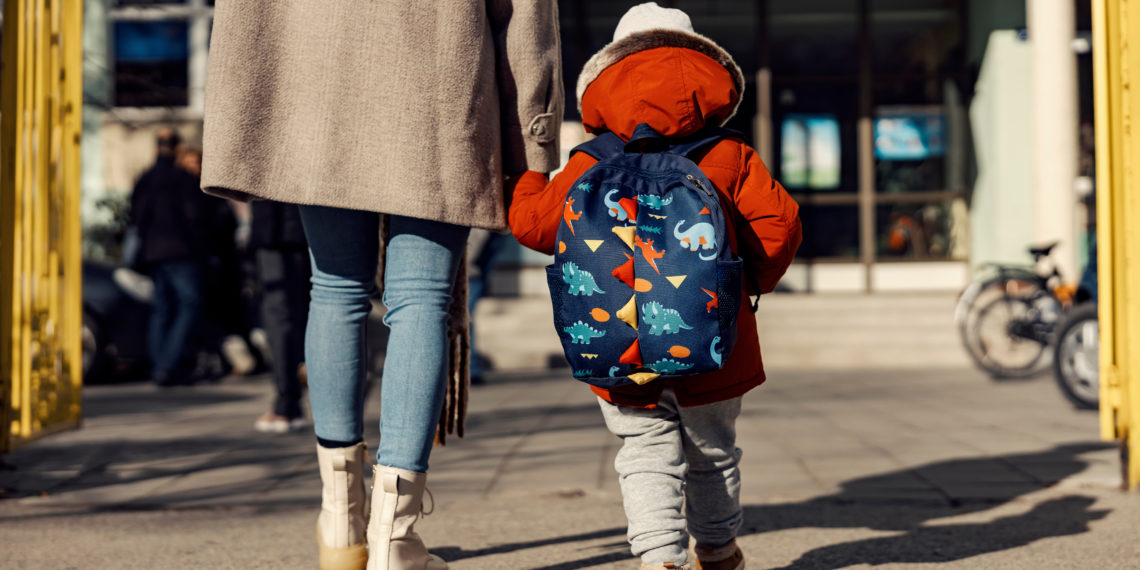 A mother entering the kindergarten yard with her preschooler boy. Childcare