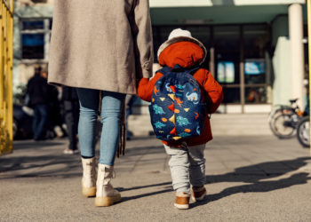 A mother entering the kindergarten yard with her preschooler boy. Childcare