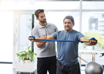 Physiotherapy, training and band with old man and doctor for stretching, rehabilitation and injury. Medical, healing and healthcare with physiotherapist and patient for consulting, help and fitness.