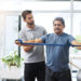 Physiotherapy, training and band with old man and doctor for stretching, rehabilitation and injury. Medical, healing and healthcare with physiotherapist and patient for consulting, help and fitness.