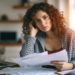 Stressed young woman reviewing her bills, reflecting financial s