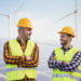 Worker men at solar power station - Solar panels with wind turbines in background - Green energy renewable concept