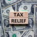 Tax relief symbol. Concept words 'tax relief' on wooden blocks on a beautiful background from dollar bills. Business and tax relief concept.