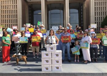 Amber England speaks before she and SQ 832 supporters submit a petition for a minimum wage increase.