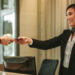 Smiling receptionist behind the hotel counter attending female guest. Concierge giving the documents to hotel guest.