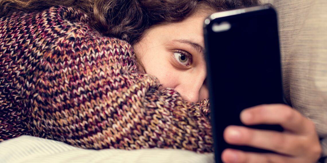 Teenage girl using a smartphone on a bed social media and addiction concept