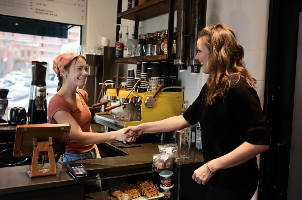 Christina Hageny meeting a local barista. Photo from Valor Payroll Solutions website.