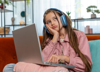 Tired young pupil girl student feeling boring with study or work at home. Stressed female teenage child exhausted from remote distance online education learning hard program on laptop computer indoors