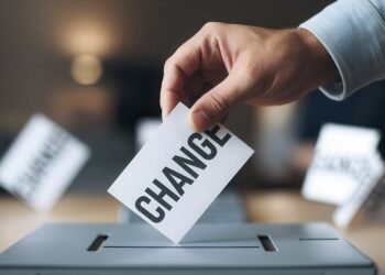 Hand casting a vote with the word CHANGE in a ballot box.