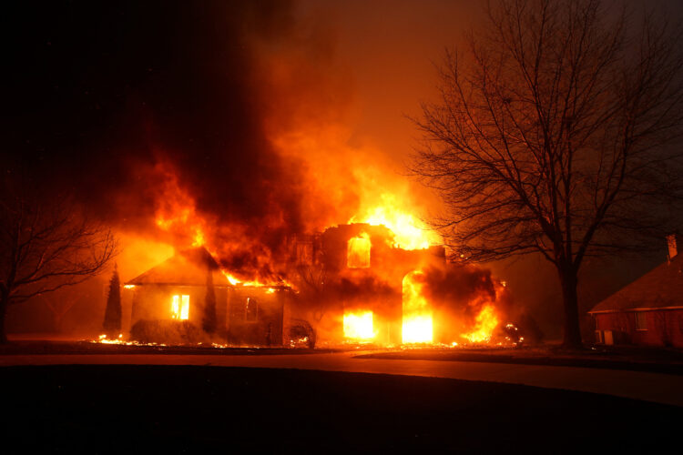 A residence burns as a wildfire outbreak spreads across Stillwater, Oklahoma, highlighting the devastation caused by wildfires to homes and communities in rural areas.