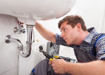 Portrait of male plumber fixing a sink in bathroom