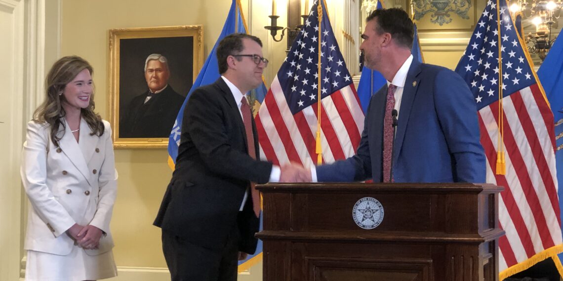 Gov. Kevin Stitt shakes Travis Jett's hand.