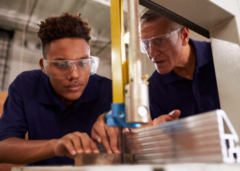 Carpenter Training Male Apprentice To Use Mechanized Saw