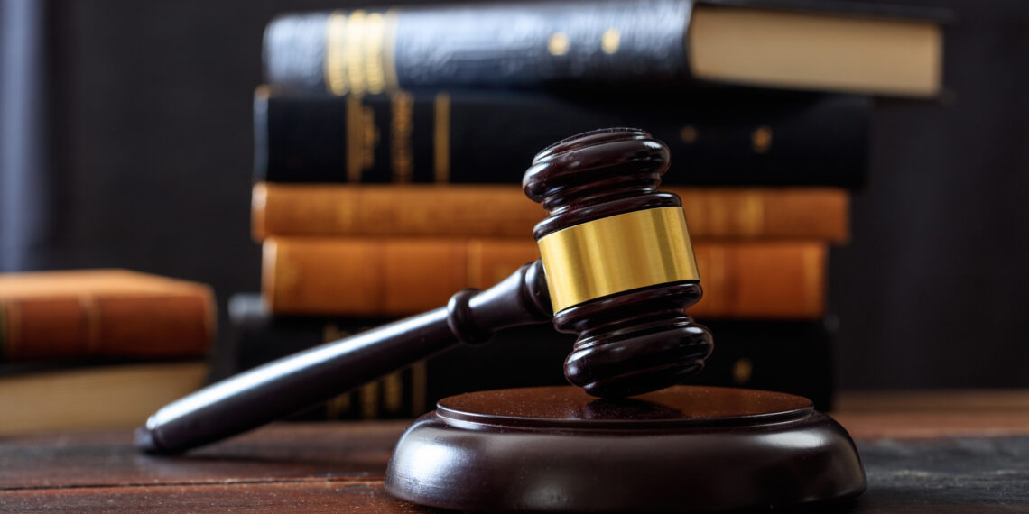 Law gavel on a wooden desk, law books background