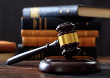 Law gavel on a wooden desk, law books background