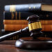 Law gavel on a wooden desk, law books background