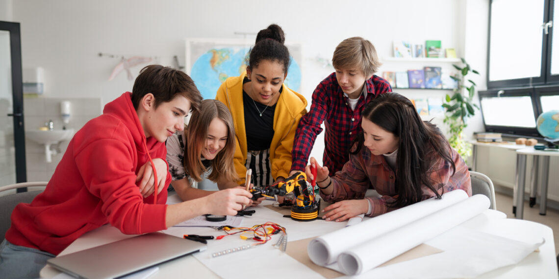 A group of students building and programming electric toys and robots at robotics classroom