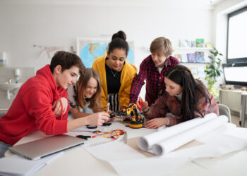 A group of students building and programming electric toys and robots at robotics classroom