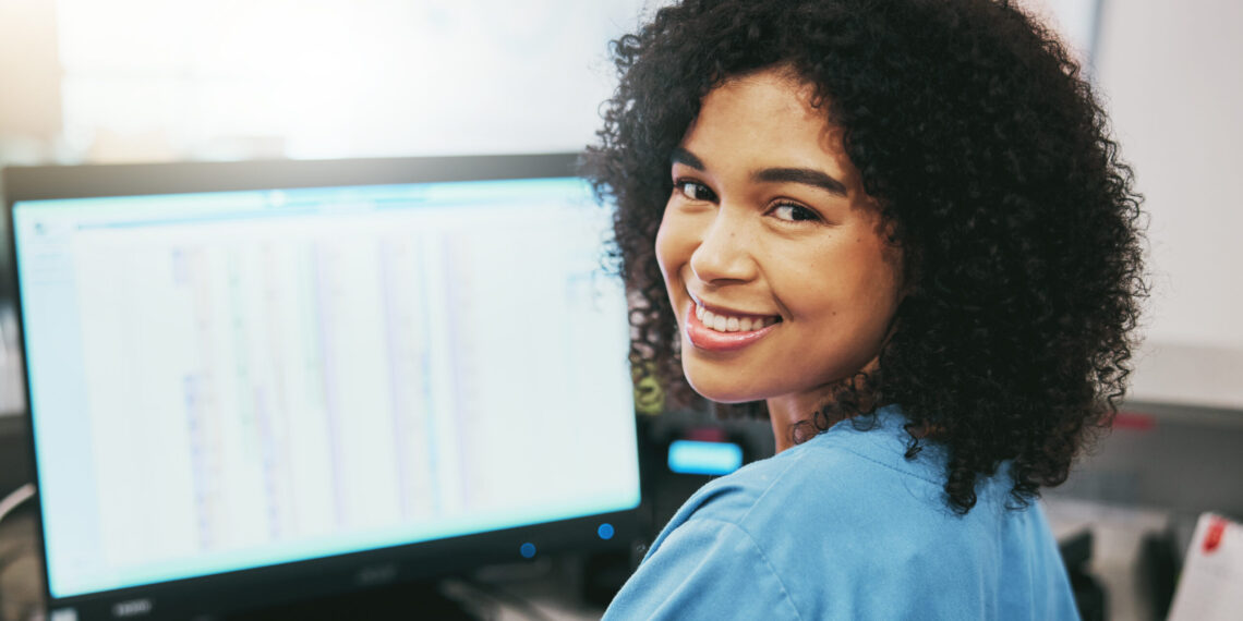 Portrait, nurse and receptionist at hospital on a computer working at her desk or table in an office as a black woman. Medical, healthcare professional or worker smile, happy and excited at work.