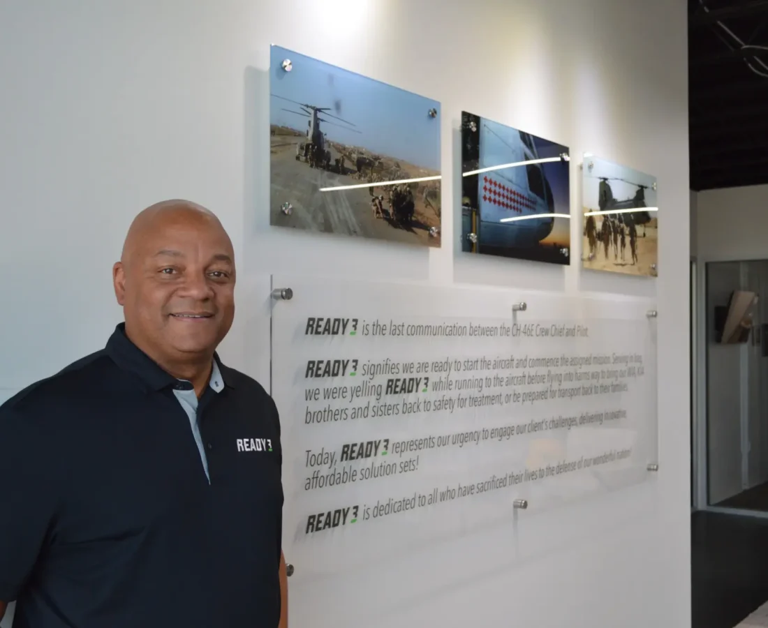 Maurice Compton standing beside the Ready 3 mission statement and military aviation photographs