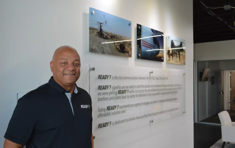 Maurice Compton standing beside the Ready 3 mission statement and military aviation photographs