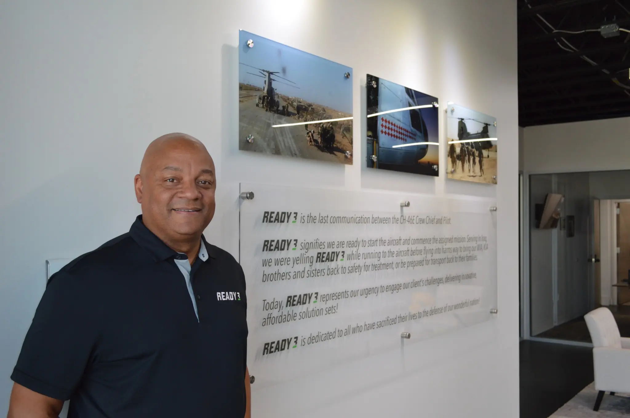 Maurice Compton standing beside the Ready 3 mission statement and military aviation photographs
