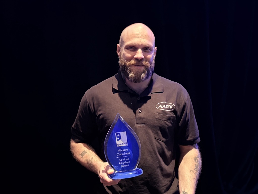 Wes Crawford holding the Spirit of Goodwill Award from Goodwill Industries of Tulsa